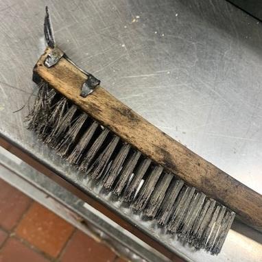 Close view of the consumer-grade scraper brush that shed a broken bristle into food
